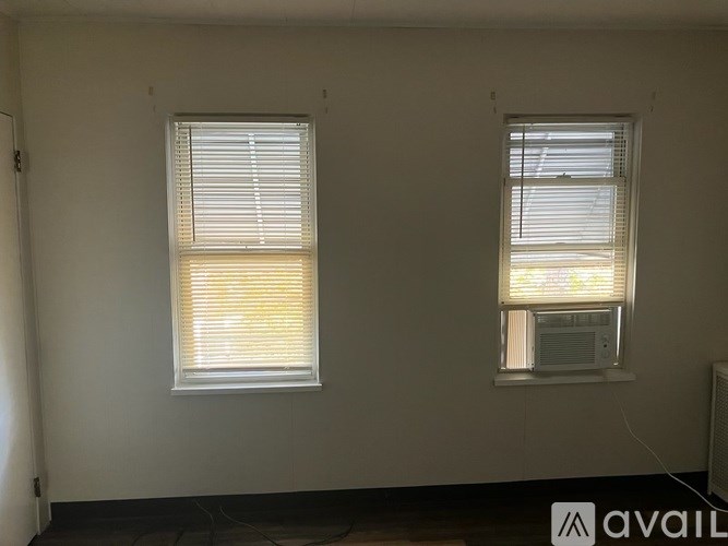 Two windows with blinds in a room with white walls.