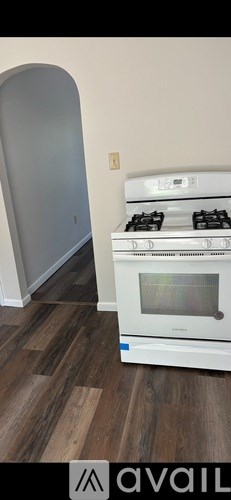 A white stove is in a room with wood flooring.