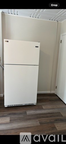 A white refrigerator in a room with wooden flooring.