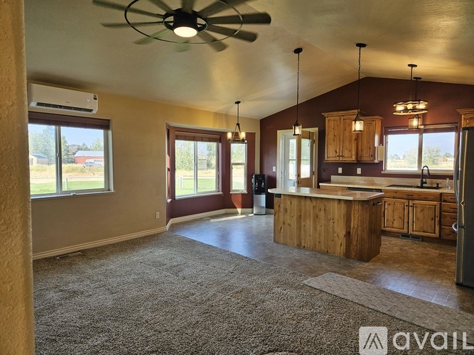 A spacious kitchen and living room with a ceiling fan and large windows.