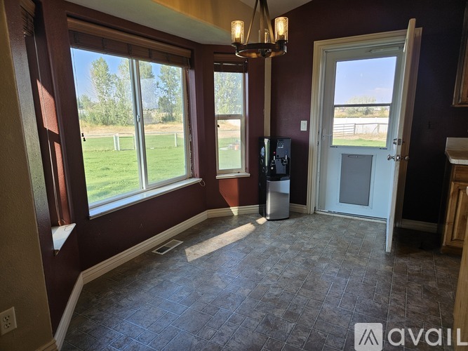A room with a chandelier, a window, and a door.