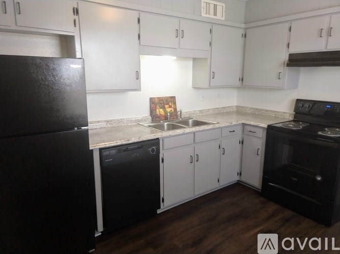 A kitchen with black appliances and white cabinets.