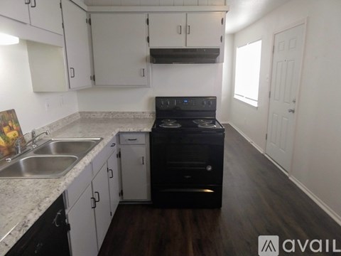 A kitchen with a black stove top oven and white cabinets.
