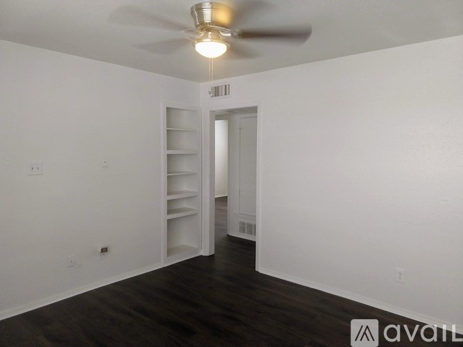 A room with a ceiling fan and a doorway leading to another room.