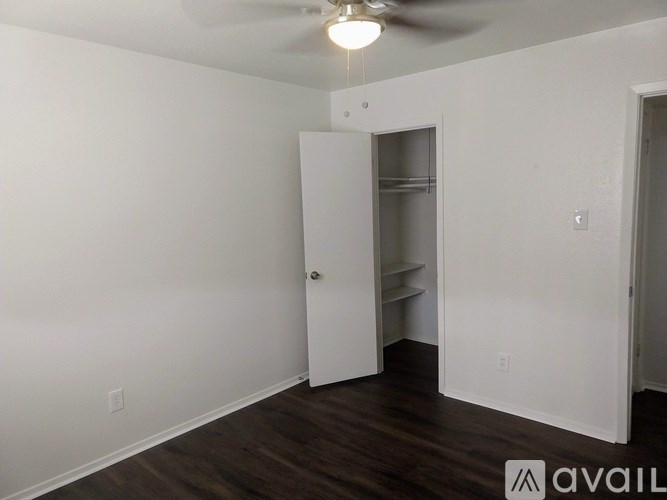 A room with a ceiling fan and a door leading to another room.