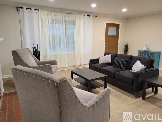 A living room with a grey couch, a grey armchair, and a black coffee table.