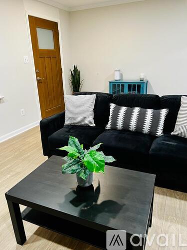 A black couch with a wooden door behind it.