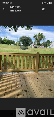 A wooden deck with a view of a grassy field and trees.