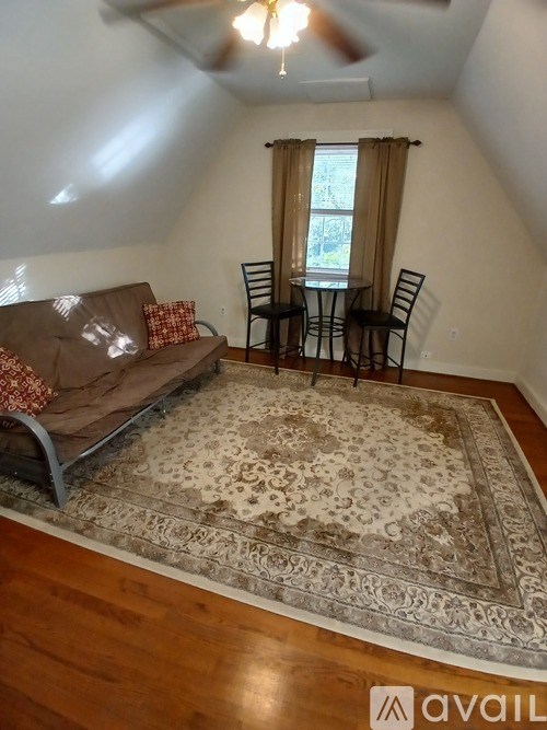 A living room with a brown couch and a rug.