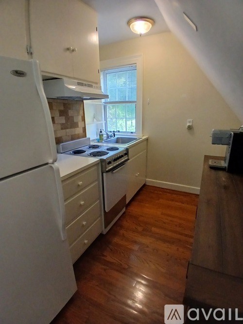 A kitchen with a white fridge and wooden floors.