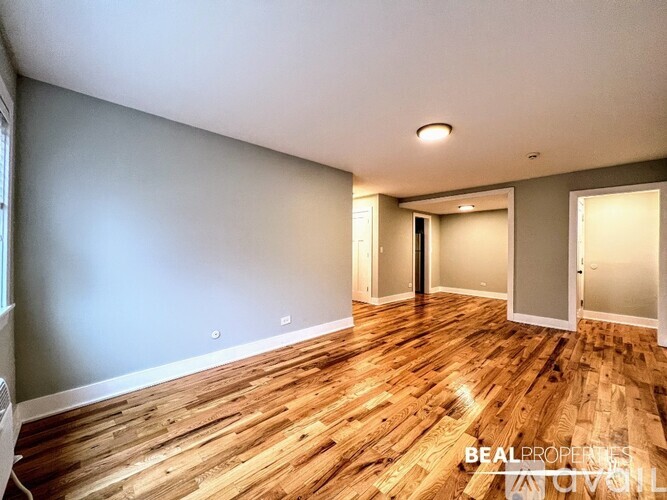 A spacious room with wooden flooring and a slanted ceiling.