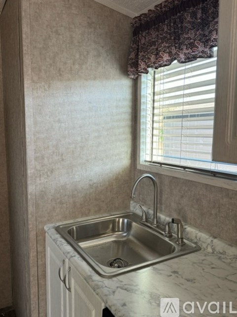 A kitchen with a sink and a window with blinds.