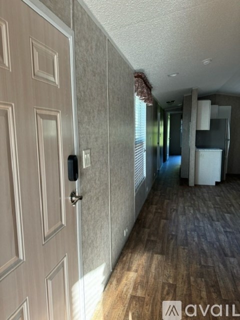 A hallway with a door on the left and a cabinet on the right.