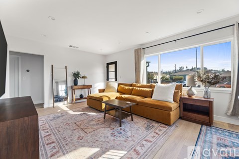 A living room with a yellow couch and a rug.