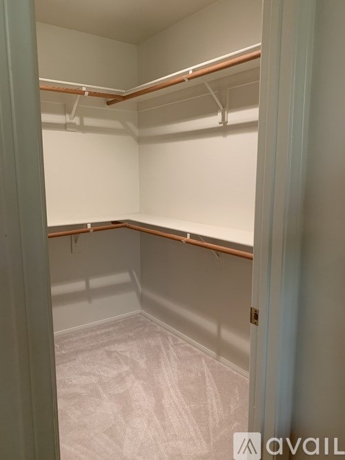 A small, empty closet with a white interior and wooden hangers.