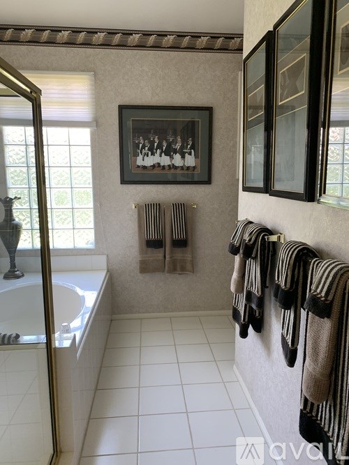 A bathroom with a white tub and a picture on the wall.