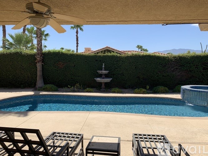 A pool with a table and chairs under a canopy.