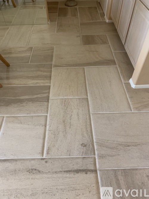 A tile floor with a wooden chair and a white cabinet.