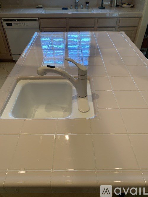 A white sink with a faucet in a tiled bathroom.
