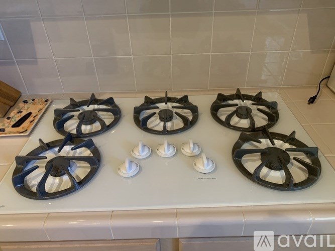 Four gas stove burners on a white countertop.
