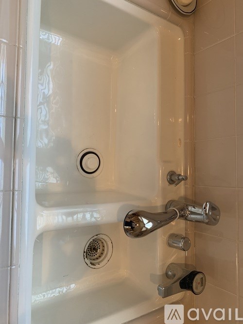 A white bathtub with a shower head and faucet.