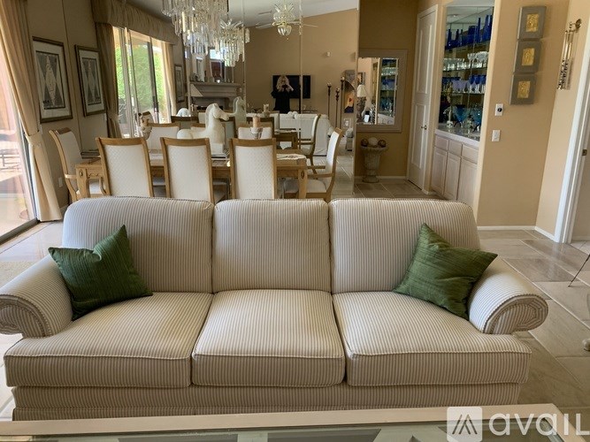 A living room with a white couch and a dining table.