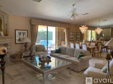A living room with a glass coffee table and a chandelier.