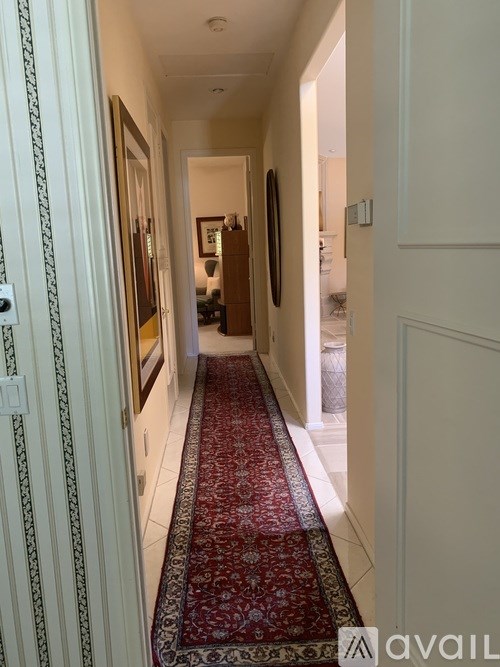 A hallway with a red carpet and white walls.