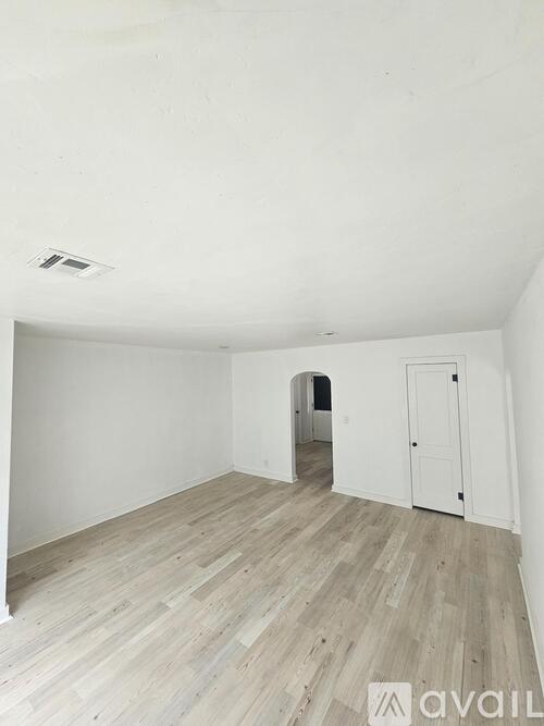 A room with wooden flooring and white walls.