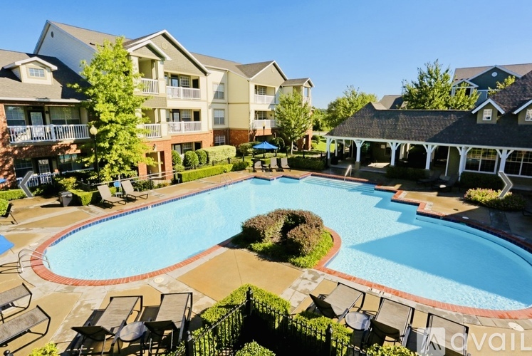 A large swimming pool surrounded by lounge chairs and apartment buildings.