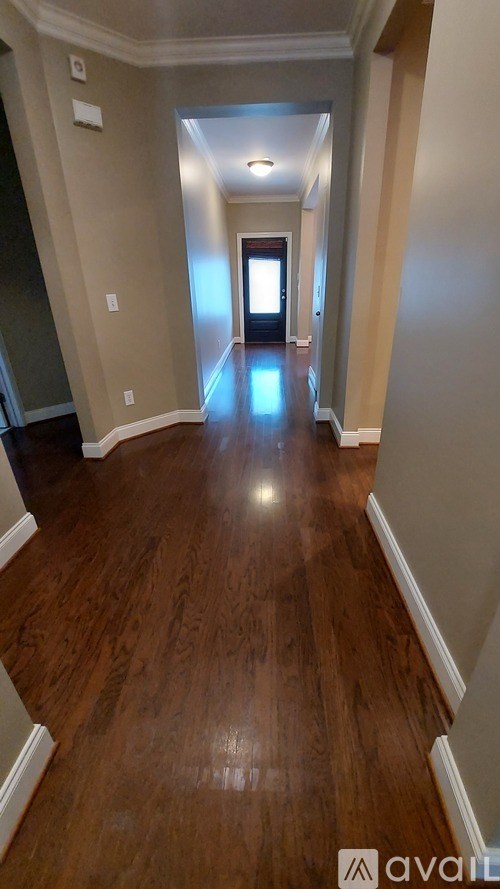 A long hallway with wood floors and white walls.