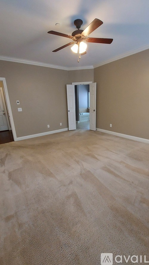 A room with a ceiling fan and carpeted floor.