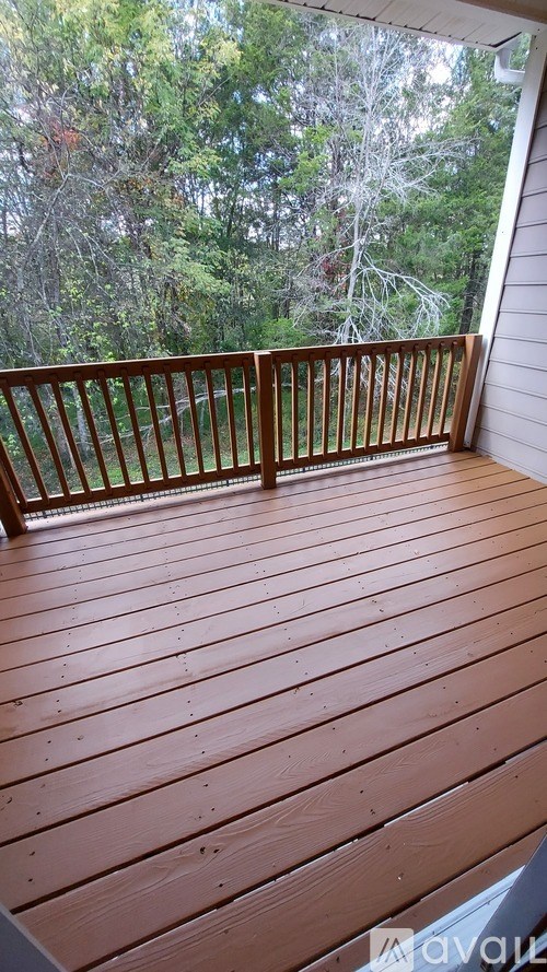 A wooden deck with a railing and trees in the background.