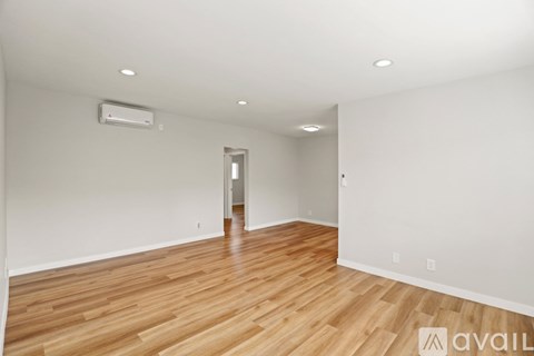 A room with wooden floors and a white wall with a doorway.