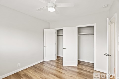 A room with a ceiling fan and three white doors.