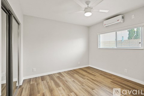 A room with a ceiling fan and a window with blinds.