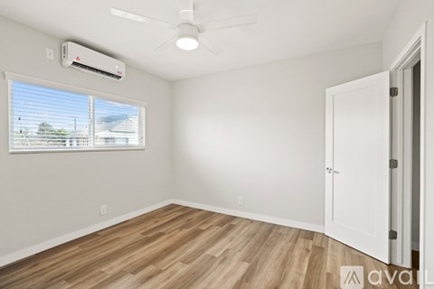 A room with a window, a ceiling fan, and a closed door.