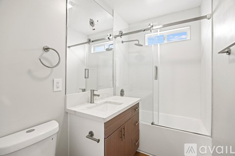 A white bathroom with a wooden vanity and a glass shower stall.