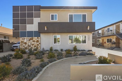 A modern house with a stone wall and a car parked in front.