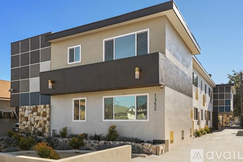 A modern house with a large front yard and a clear blue sky above.