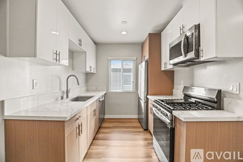 A kitchen with wooden cabinets and stainless steel appliances is available for rent.