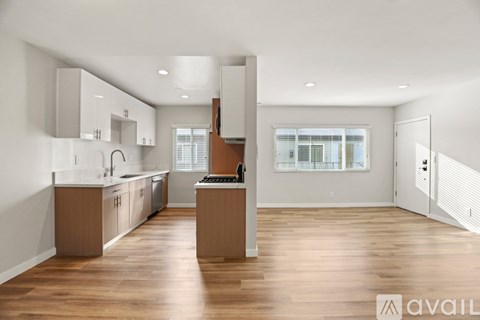 A modern kitchen with wooden floors and white walls.