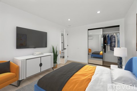 A bedroom with a bed, a chair, a cabinet, a mirror, and a television.