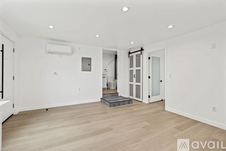 A spacious room with wooden flooring and white walls.