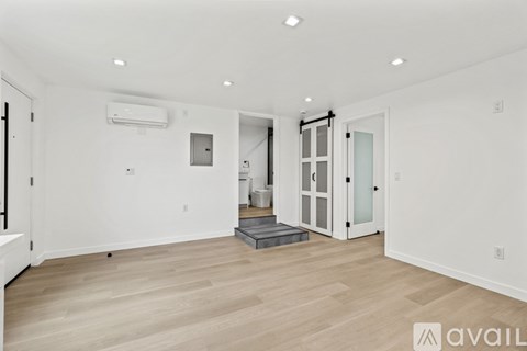 A spacious room with wooden flooring and white walls.