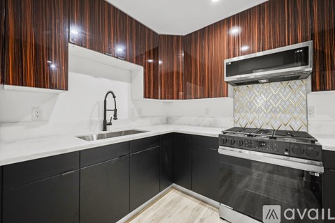 A kitchen with a black oven and wooden cabinets.