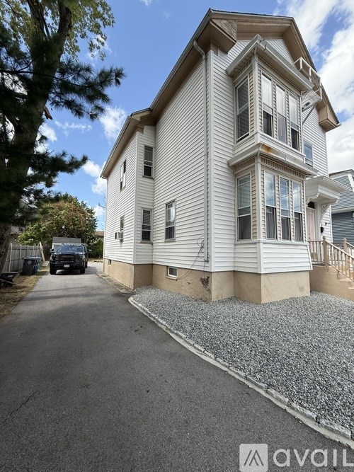 A house with a white exterior and a gravel driveway.