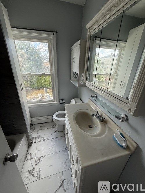 A bathroom with a marble floor and a large mirror.
