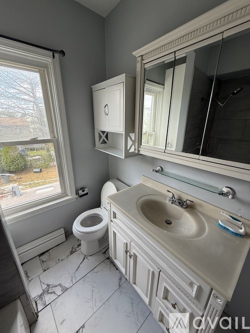 A bathroom with a toilet, sink, and mirror.