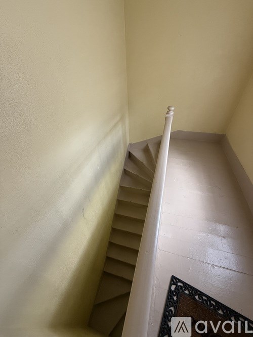 A staircase with a metal railing and a brown carpet with the word "available" on it.